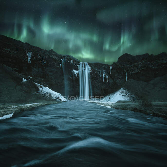 Aurora borealis over beautiful Icelandic waterfall — Stock Photo