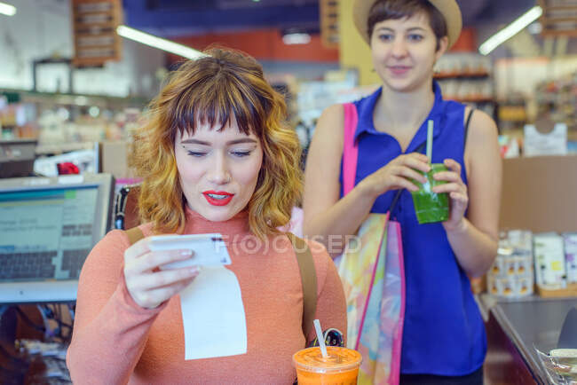 Дві жінки в магазині платять за свіжі сокові напої — стокове фото