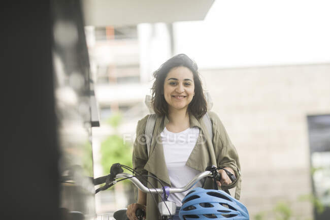 Smiling woman standing by her bicycle — Stock Photo