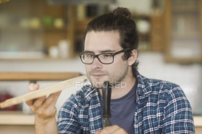 Man standing in kitchen making a homemade chopping board — Stock Photo