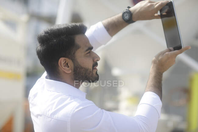 Man standing outdoors taking a photo using a digital tablet — Stock Photo