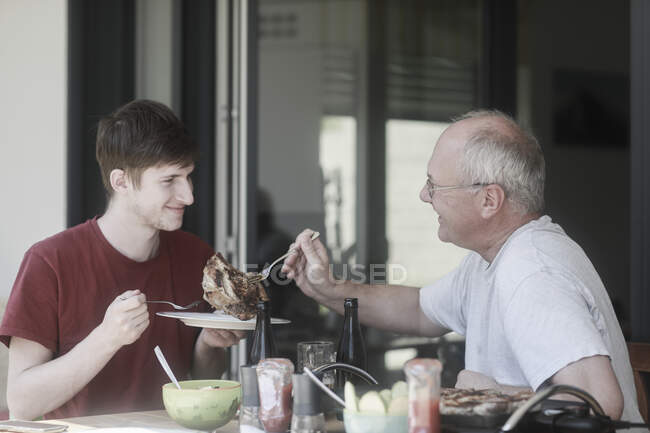 Adult father serving barbecued steak to his son — Stock Photo