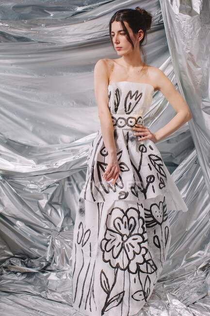 Жінка в паперовій сукні на глянсовому фоні — стокове фото