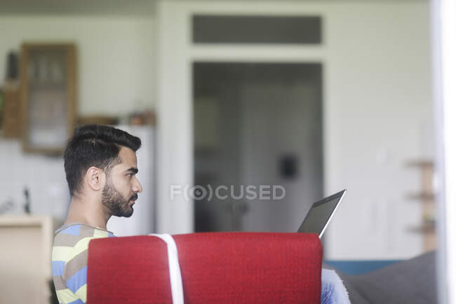 Man sitting in an armchair working on his laptop computer — Stock Photo