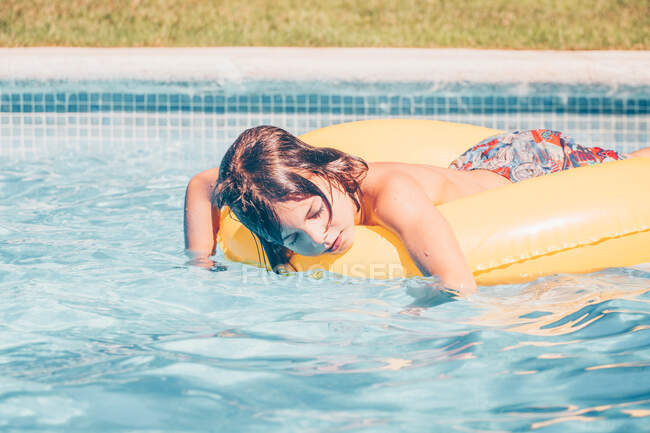 Menino relaxante em um anel de borracha inflável em uma piscina — Fotografia de Stock