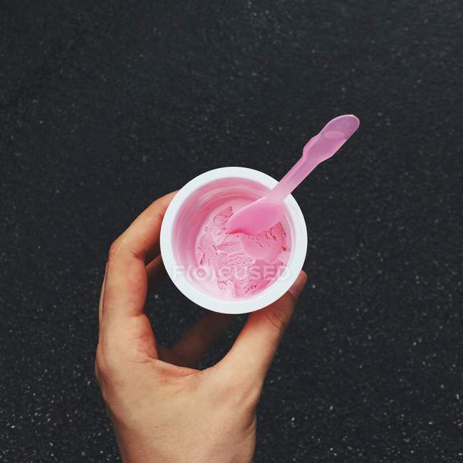 Main humaine tenant une tasse de glace à la fraise — Photo de stock
