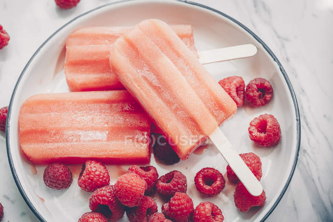 Three strawberry ice-creams and raspberries on a plate — Stock Photo