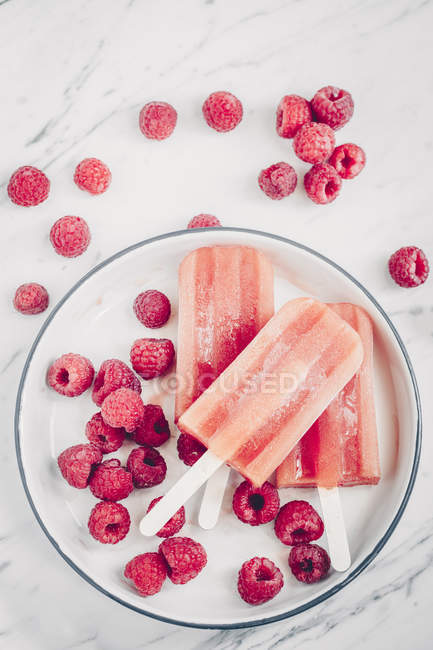 Three strawberry ice-creams and raspberries on a plate — Stock Photo