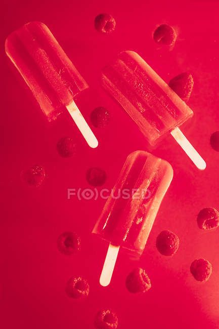 Drei Erdbeereis mit Himbeeren, roter Hintergrund — Stockfoto