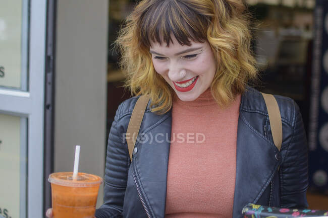 Donna sorridente che tiene in mano una bevanda di succo — Foto stock