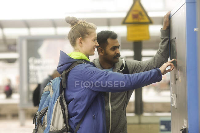 Couple at a train station buying a ticket from a ticket machine — Stock Photo