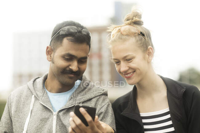 Улыбающаяся пара смотрит на мобильный телефон — стоковое фото