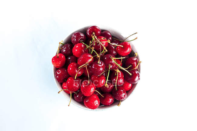 Overhead view of a bowl of cherries over white background — Stock Photo