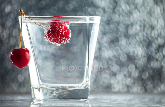 Closeup view of Glass of water with a fresh cherry — Stock Photo