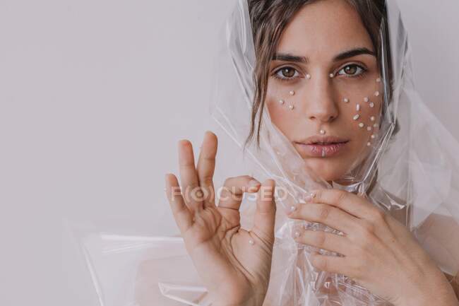 Портрет женщины с жемчугом на лице, завернутой в прозрачный пластик — стоковое фото