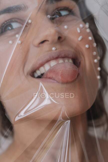 Портрет жінки з перлами на обличчі загорнута в прозорий пластик. — стокове фото