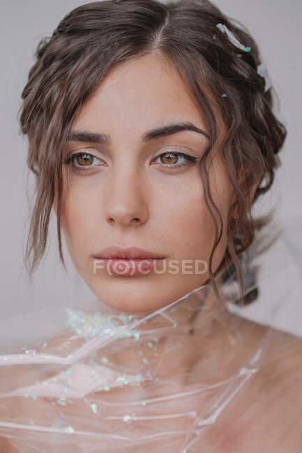Retrato de uma mulher envolta em plástico sobre fundo branco — Fotografia de Stock
