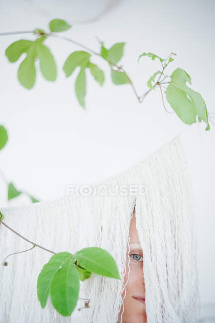 Mulher olhando através de uma cortina franja — Fotografia de Stock