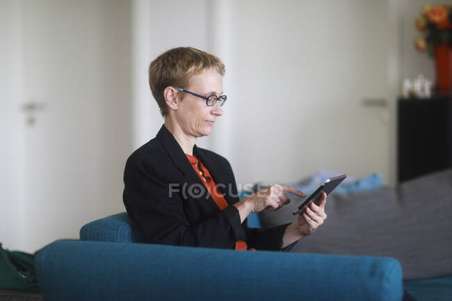 Frau sitzt mit digitalem Tablet auf der Couch — Stockfoto