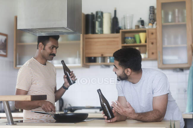 Two men drinking beer while cooking dinner — Stock Photo