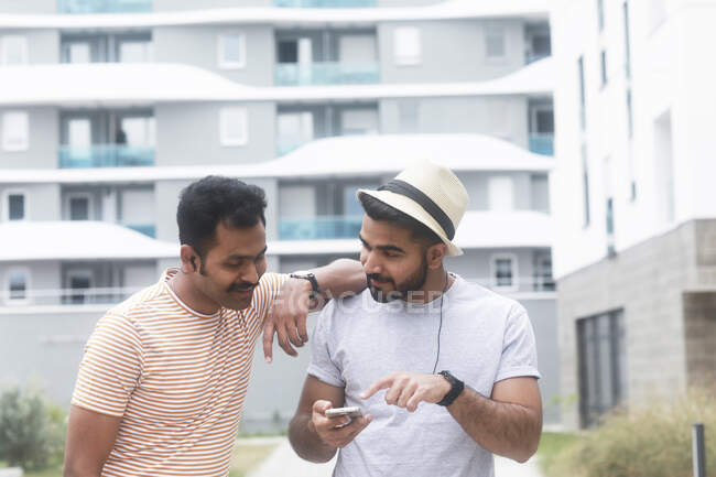 Deux hommes écoutent de la musique sur leur téléphone portable — Photo de stock