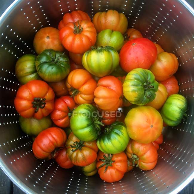 Green and red tomatoes in a colander, closeup view — Stock Photo