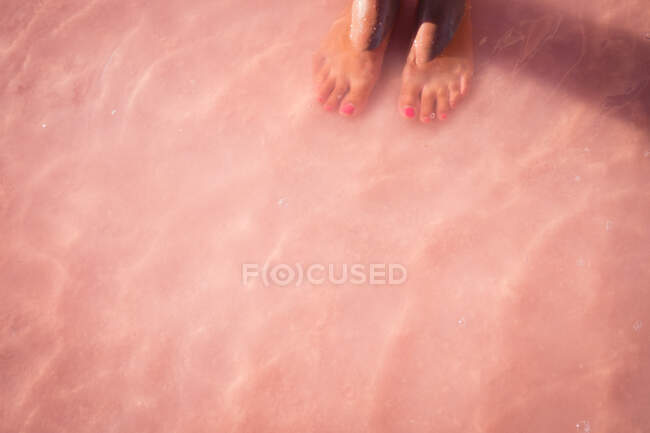 Primer plano de los pies de una niña en aguas poco profundas en el océano, Australia - foto de stock