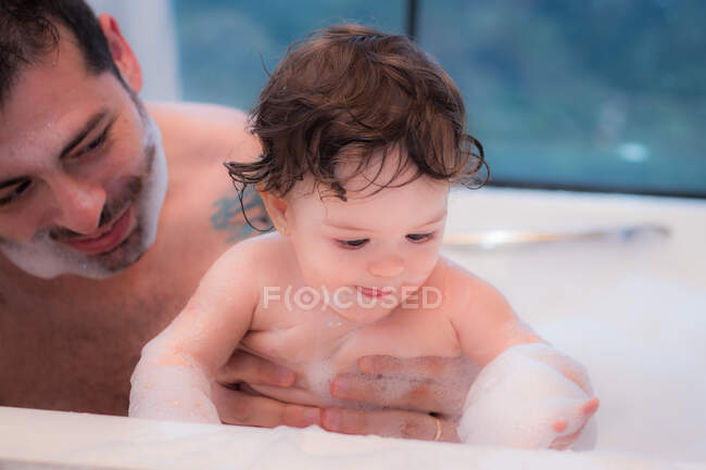 Padre dándole un baño a su hija - foto de stock