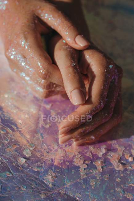 Vista de cerca de las manos femeninas cubiertas de brillo - foto de stock