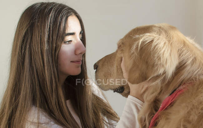 Chica acariciando su perro recuperador de oro - foto de stock