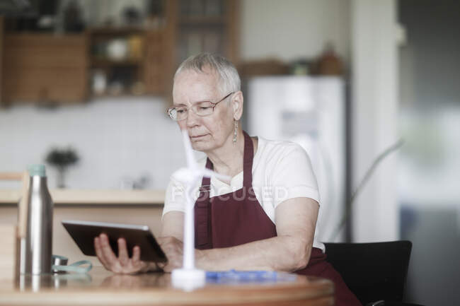Woman sitting at a table fixing a lamp — Stock Photo