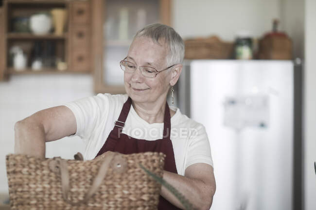 Женщина, стоящая на кухне, распаковывает свою сумку — стоковое фото