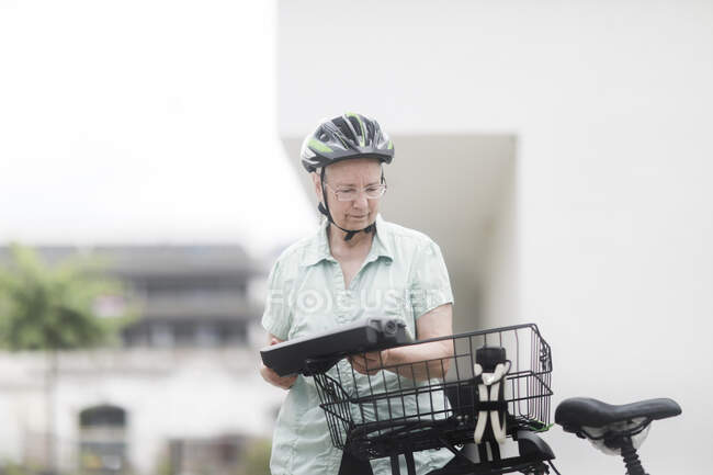 Mujer reemplazando la batería en su e-bike - foto de stock
