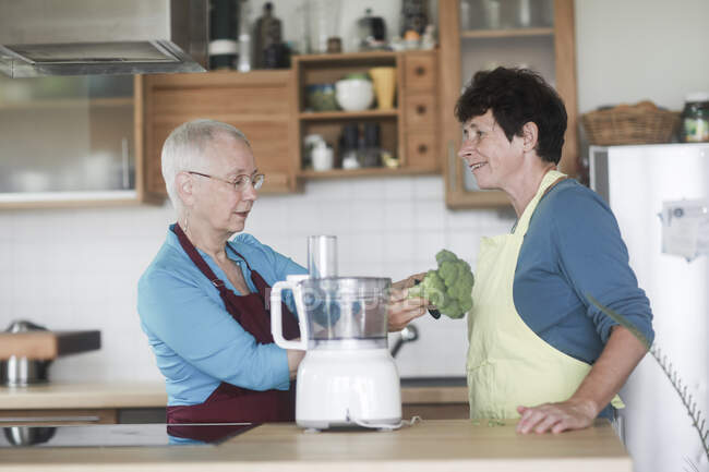Две женщины стоят на кухне и готовят брокколи. — стоковое фото