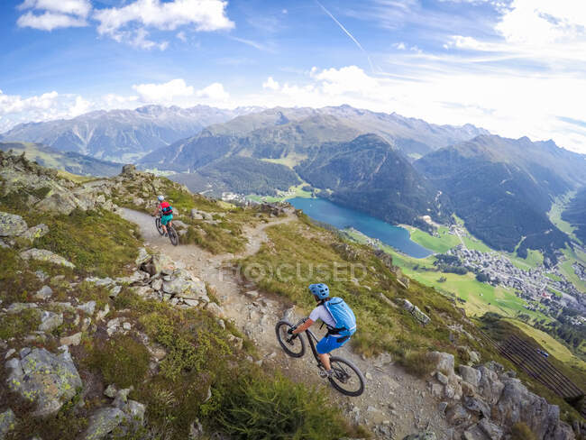 Dos mujeres en bicicleta de montaña en los Alpes suizos cerca de Davos, Graubunden, Suiza - foto de stock