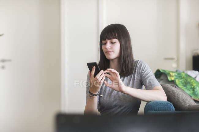 Woman sitting on a couch using a mobile phone — Stock Photo