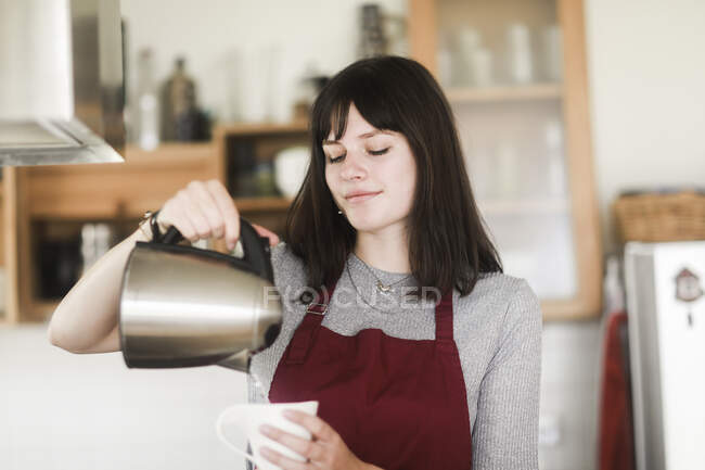 Donna che versa acqua bollente in una tazza — Foto stock