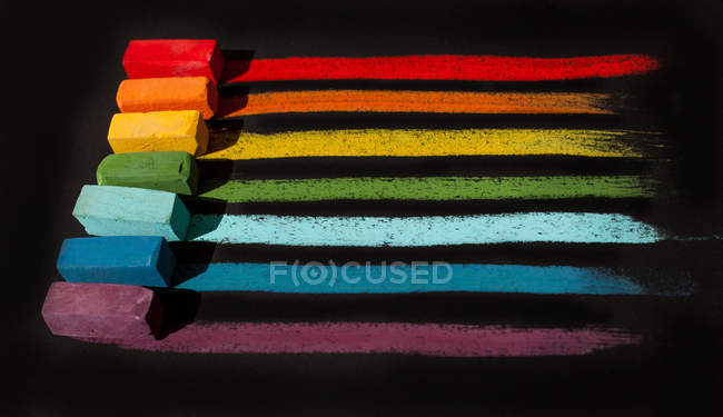Multi-colored soft oil pastels in a row on black background — Stock Photo