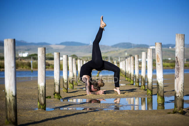 Woman on Los Lances beach doing a forearm stand wheel pose, Tarifa, Cadiz, Andalusia, Spain — Stock Photo