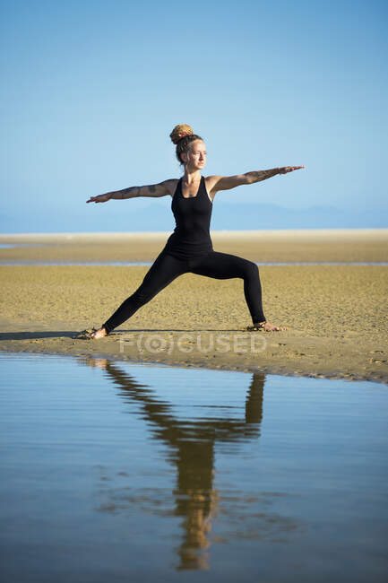 Frau am Strand von Los Lances in Krieger II Yoga-Pose, Tarifa, Cadiz, Andalusien, Spanien — Stockfoto