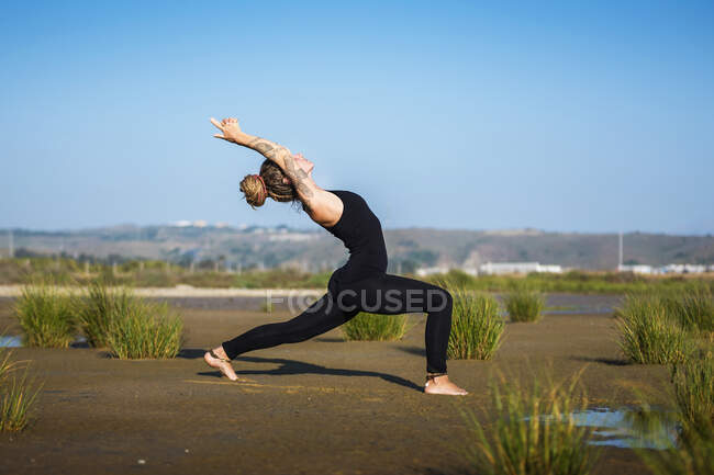 Woman on Los Lances beach doing warrior I yoga pose, The Strait Natural Park, Tarifa, Cadiz, Andalusia, Spain — Stock Photo