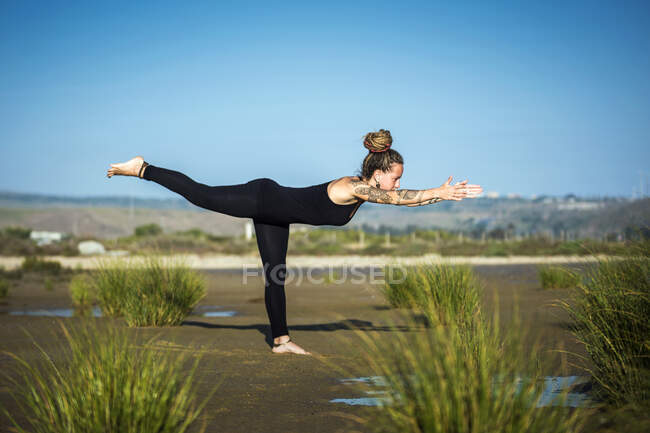 Woman on Los Lances beach doing warrior III yoga pose, The Strait Natural Park, Tarifa, Cádiz, Andaluzia, Espanha — Fotografia de Stock