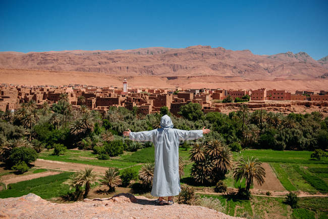 Homme debout les bras tendus près d'une kasbah, Ouarzazate, Maroc — Photo de stock