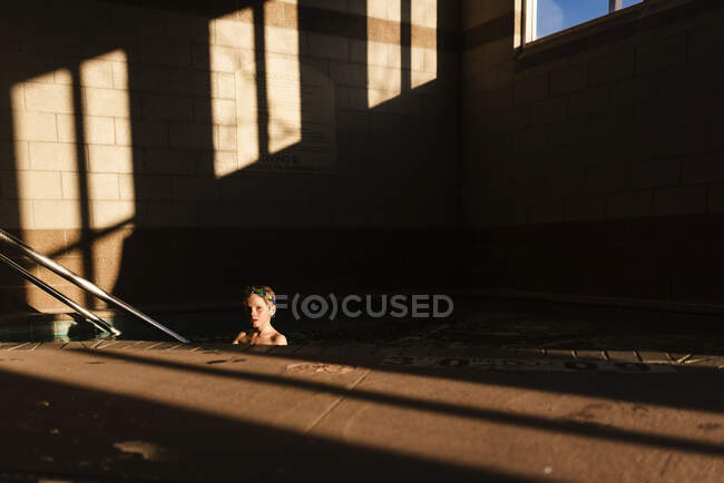 Menino em uma piscina nas sombras — Fotografia de Stock