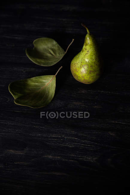 Pear and leaves on a table, closeup view — Stock Photo