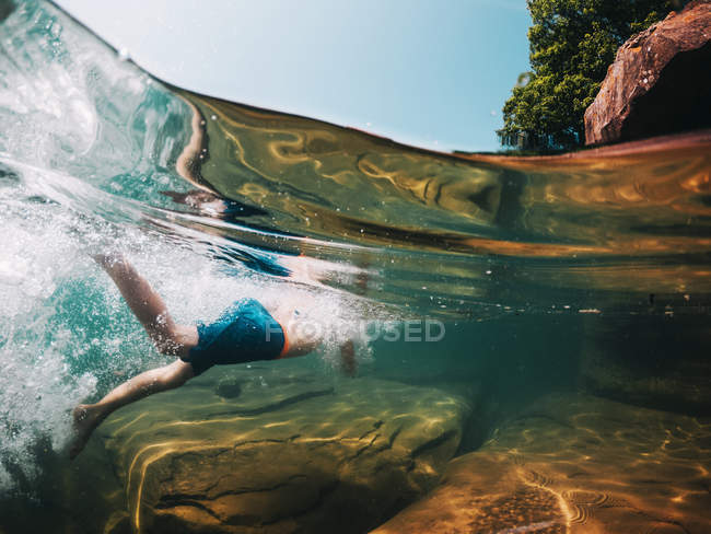 Мальовничий вид на молодого хлопчика, який плаває в чистому красивому озері — стокове фото