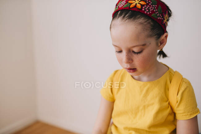 Retrato de una chica sentada en un taburete mirando hacia abajo - foto de stock