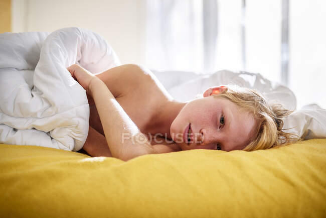 Menino deitado na cama acordando — Fotografia de Stock
