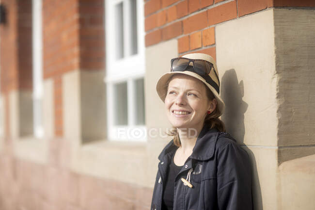 Portrait of a smiling woman standing in street leaning against a wall — Stock Photo