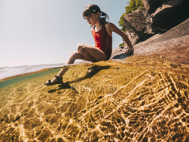 Mädchen sitzt auf einem Felsen in Lake Superior, USA — Stockfoto